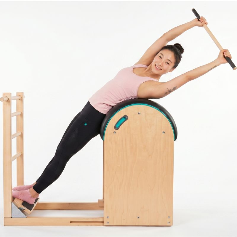 Golfer rotates her core on the Pilates Ladder Barrel to improve her stability, her swing, and reduce back pain